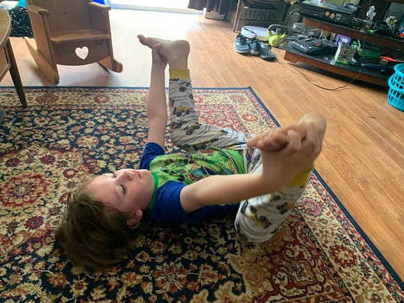 boy on the floor in happy baby yoga position