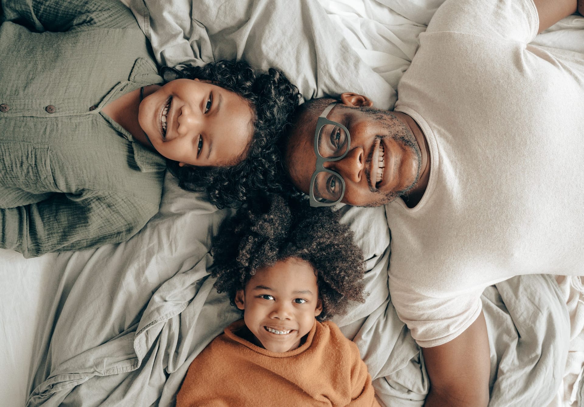 Black family lying on bed smiling up at ceiling